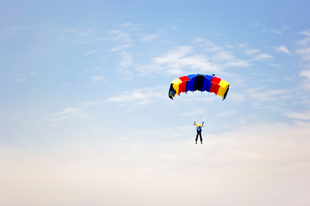 Red, yellow and blue parachute against cloudy sky