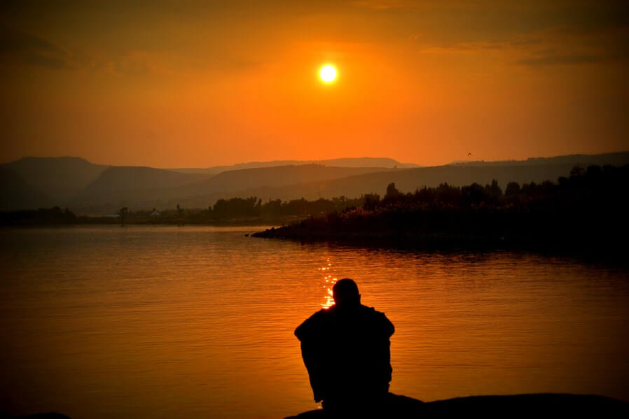 alone man sitting watching the sunset