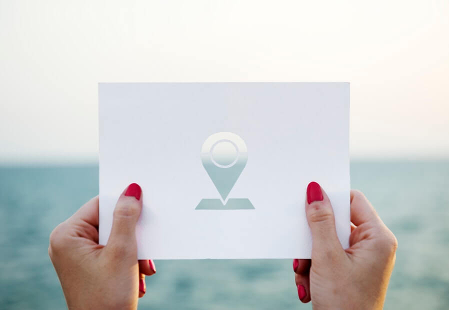 person holding paper with Geolocation icon