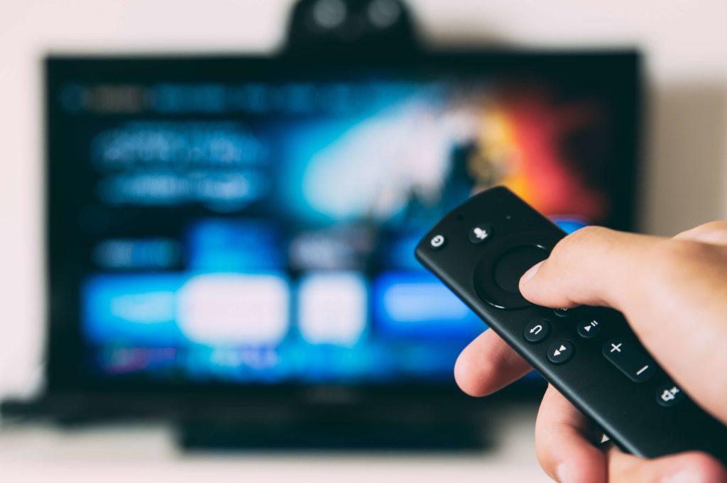 Person holding a remote watching TV