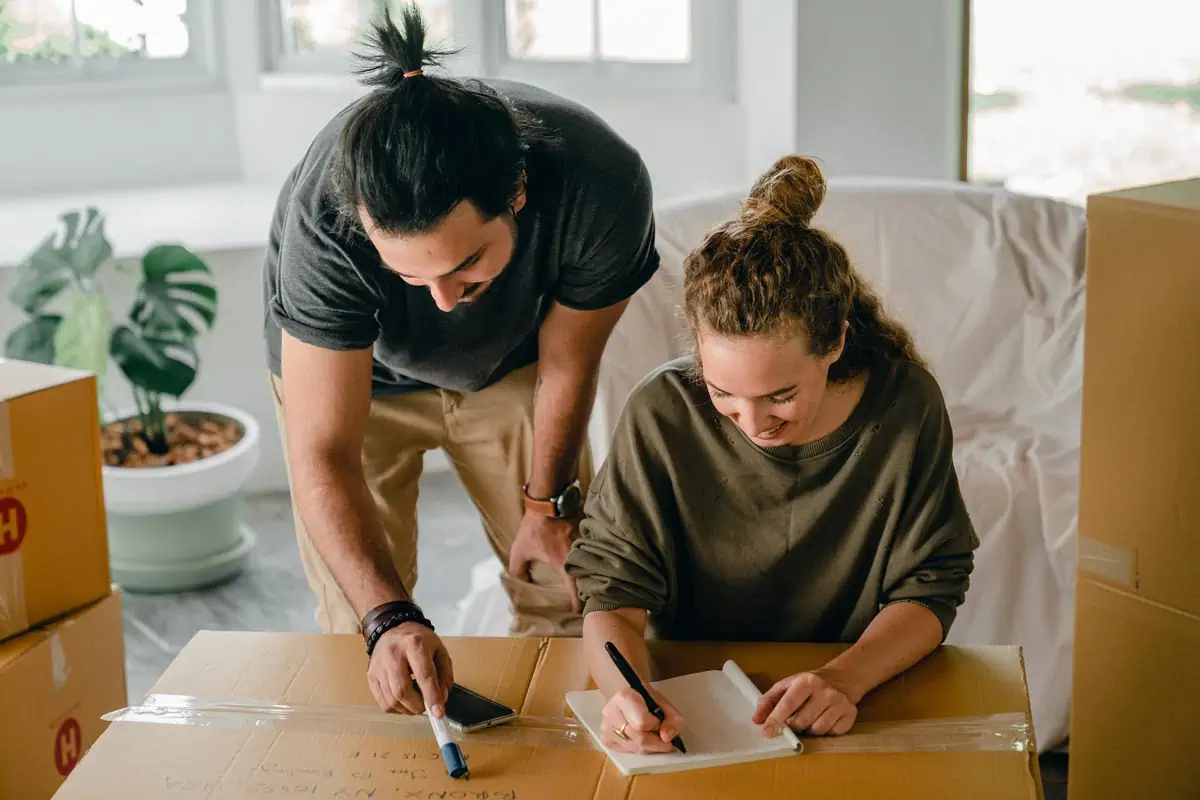 Cheerful diverse couple writing in notebook