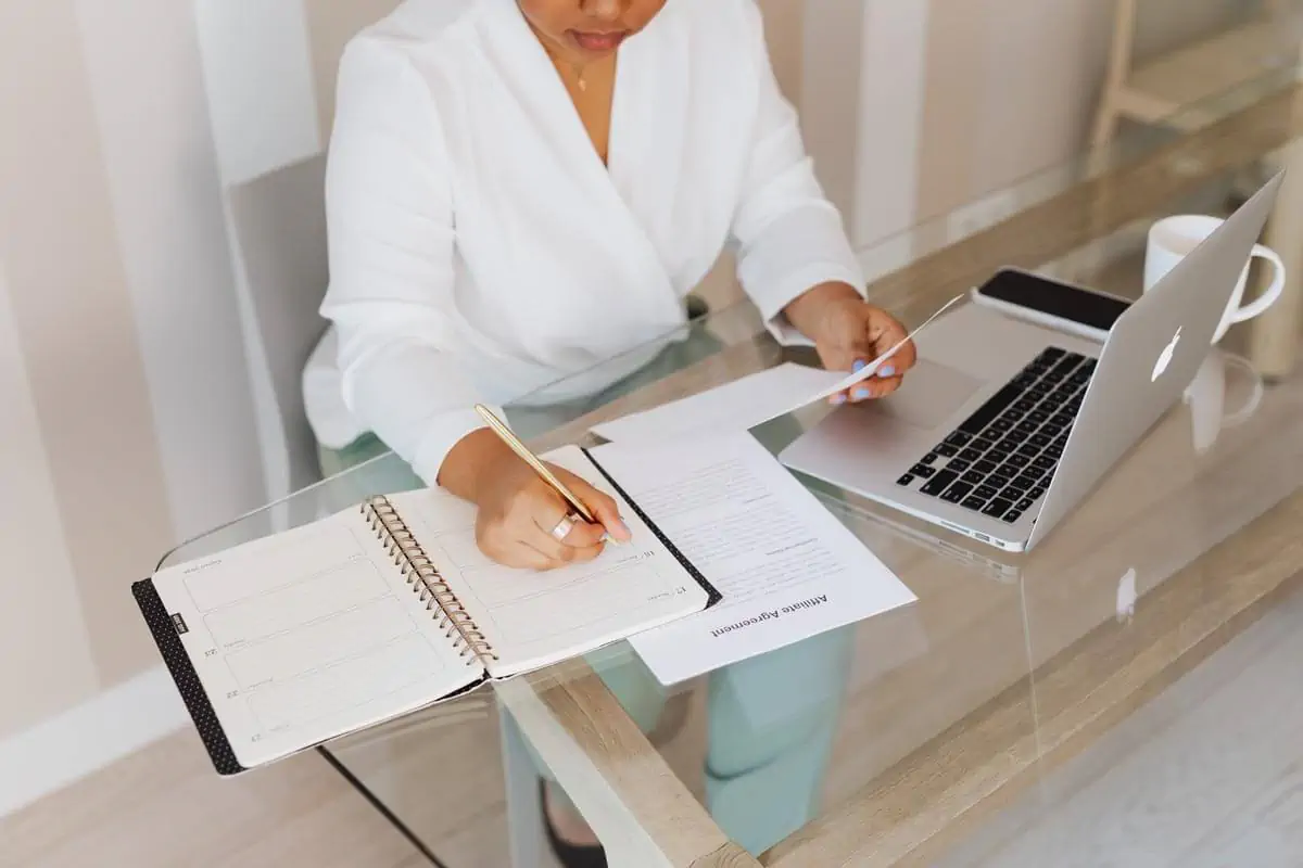 Professional writing notes infront of laptop