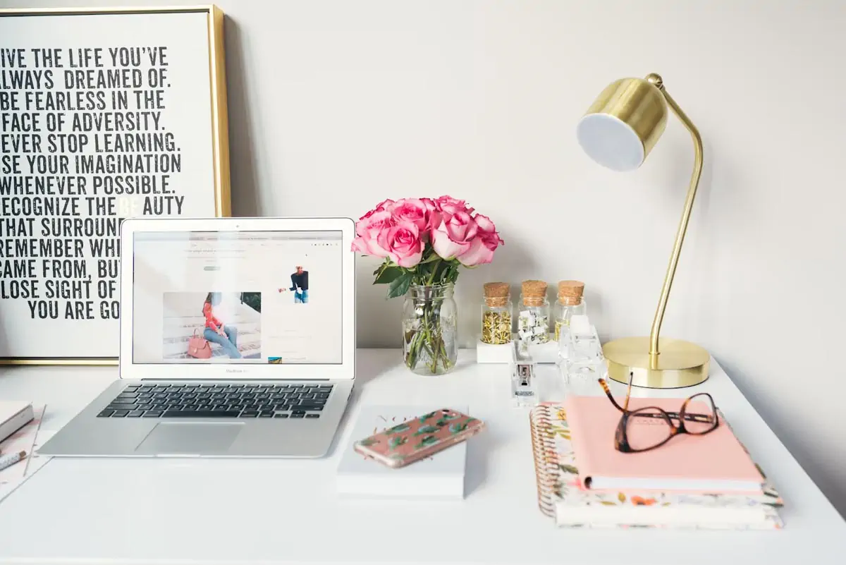 macbook air beside gold colored study lamp and spiral books