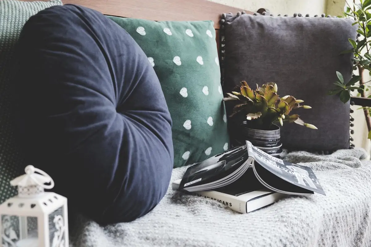 two books beside three assorted color pillows