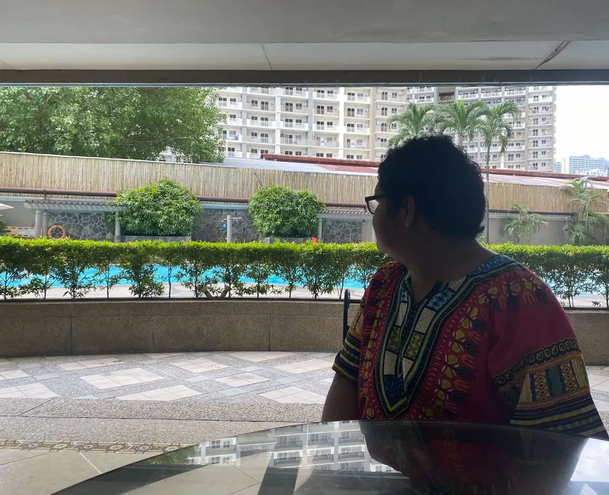 man looking at pool beside high building